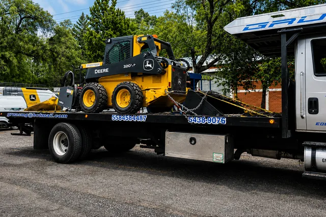 Minicargador John Deere amarrado con cadenas sobre la plataforma de Grúas MG